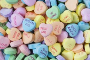 various candy hearts saying love bug, text me, soul mate