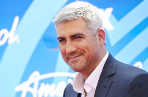 Taylor Hicks poses for a photo with the American Idol logo in the background