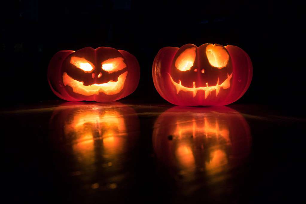 Two jack-o-lanterns lighted up against a black background