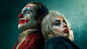 Official promotional material for Joker: Folie à Deux. The Joker, Joaquin Phoenix, stands back to back with Harley Quinn, portrayed by Lady Gaga, as she smokes a cigarette.