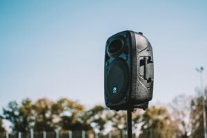 A speaker on a pole outdoors with blue sky background